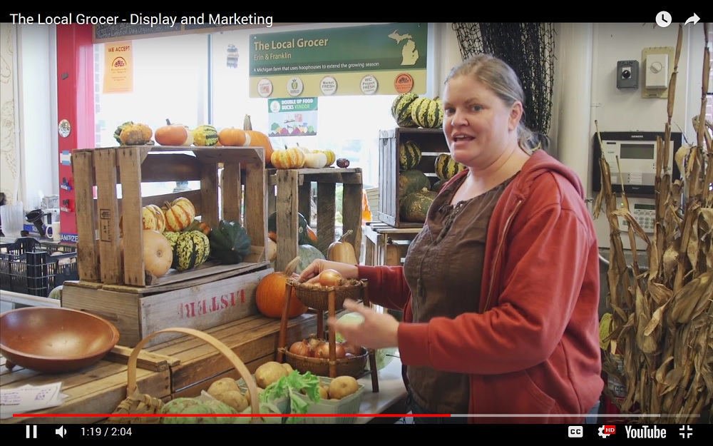 Screen capture of a video showing a woman demonstrating how to display vegetables for sale