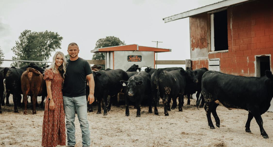 Couple in front of barn and cows at Lane View Farm in Cement City  Michigan