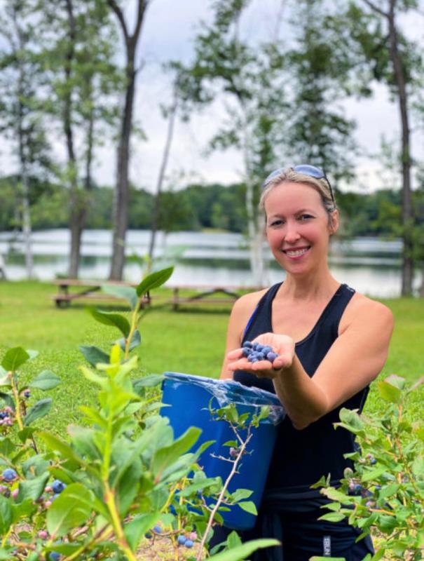 Woman picking blueberries by a lake at Russell's Blueberry Farm