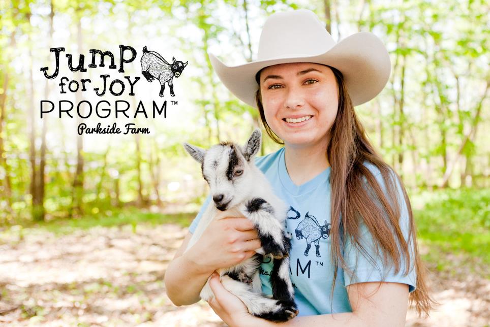 Woman in white cowboy hat with pygmy goat