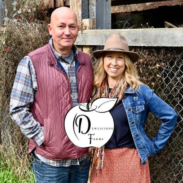 Couple in front of apple orchard at Dewlicious Farms in Manistee