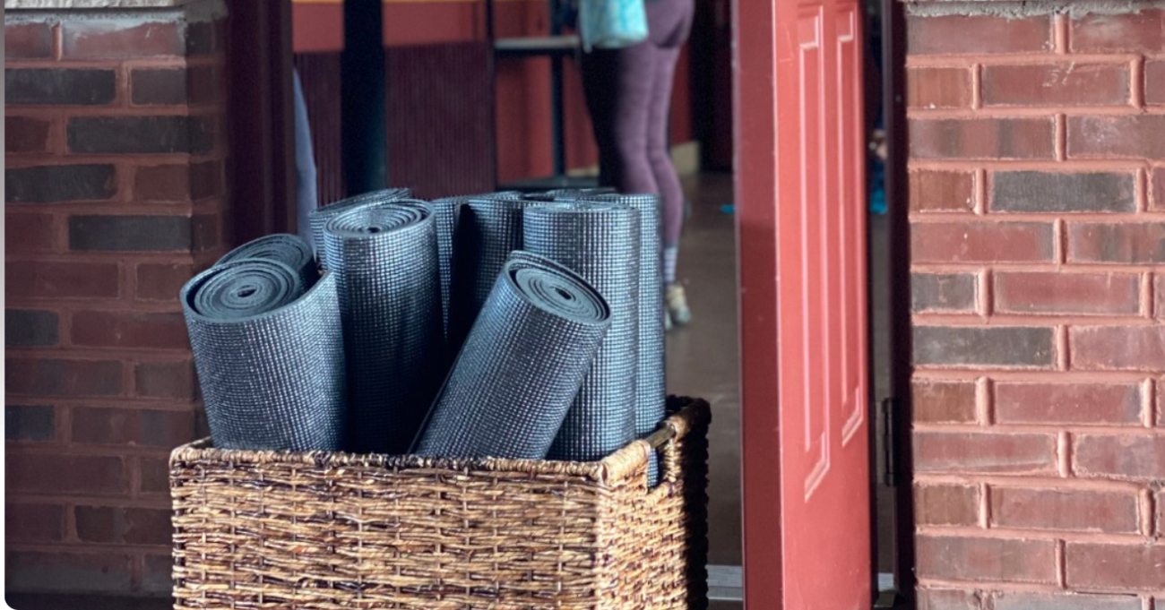 Yoga mats in basket, brick wall