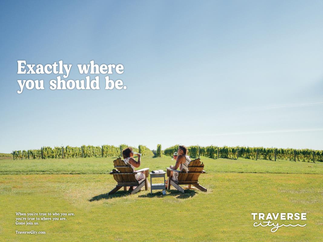 women drinking wine in chairs in vineyard